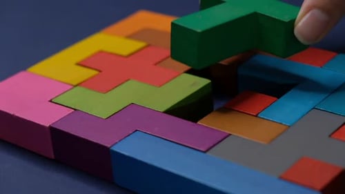 Nahaufnahme in Zeitlupe, Hand haltendes Stück eines Holzblock-Puzzles, Holzwürfel, Stapeln von Würfeln, Konzept eines Komplexes