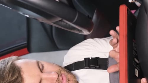 A Professional Car Mechanic Examines a Car at a Car Service Performing a Series of Tests