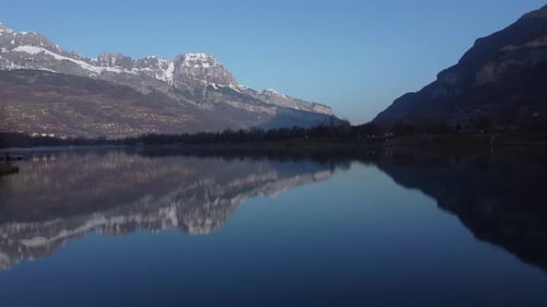 Aerial showing the reflections of the snowy mountains on the Passy lake. French Alps