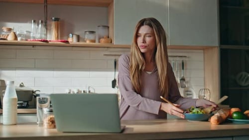 Woman Cooking with Laptop in Kitchen