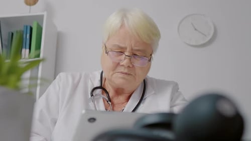 Female doctor using tablet to process patients data for medical analysis.