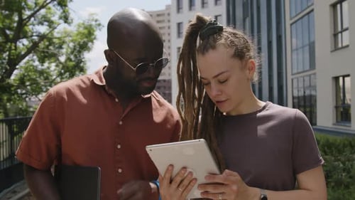 Diverse Colleagues Brainstorming Ideas Looking at Tablet in Urban Park