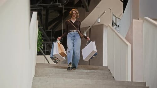 Jeune fille portant des sacs de vente au détail descendant dans un centre commercial moderne