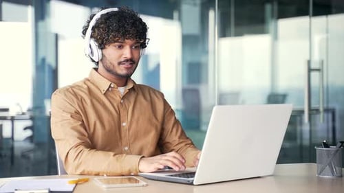 Young Adult Working on Laptop with Headphones On