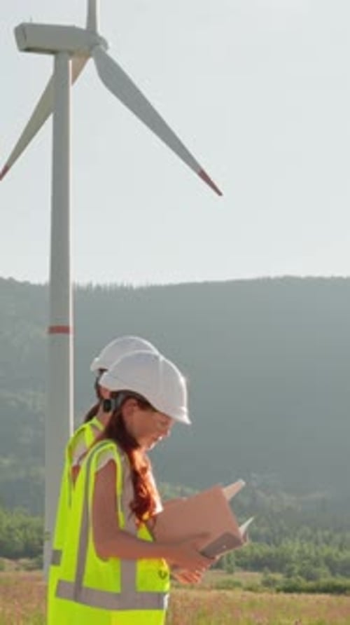 A Dedicated Young Engineer Diligently Inspects the Wind Turbine Site Ensuring Every Detail is
