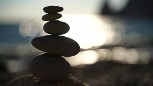 Balanced Pebble Pyramid on the Beach on a Sunny Day Abstract Sea Bokeh From Sunset on Background