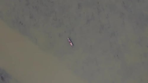 Traditional wooden fishing boat in endless dirty lake water, aerial top down view