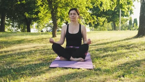Woman Meditating in Park on Yoga Mat