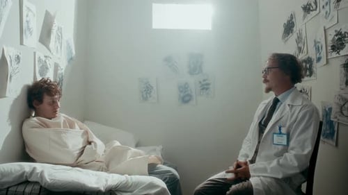Adult Doctor Talking with Young Patient in Hospital Room