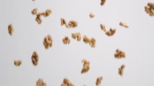 Falling Walnut Pieces Against White Background