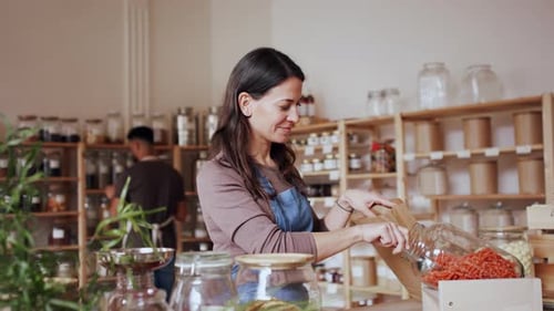 Mujer llenando una bolsa de papel con pasta en Zero Waste Shop