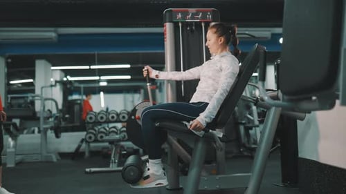 Mulher determinada treinando pernas na máquina de extensão no ginásio