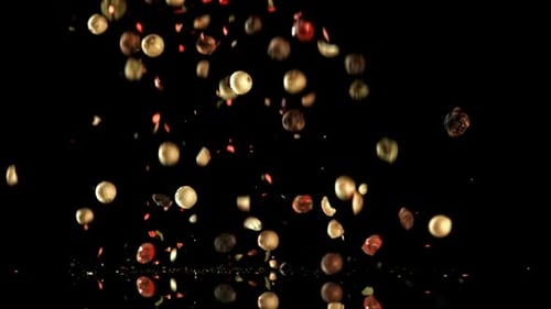 Pepper medley falling on a reflective black surface