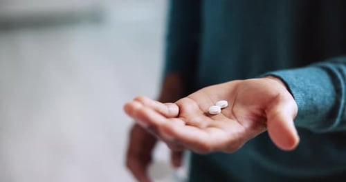 Person Taking White Pills From Bottle By Hand
