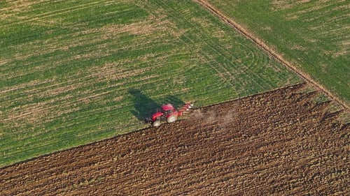 Tractor tilling lush farmland at sunset for the upcoming planting season