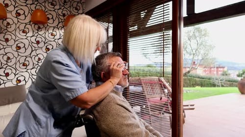 Krankenschwester passt die Brille eines älteren Mannes im Rollstuhl an