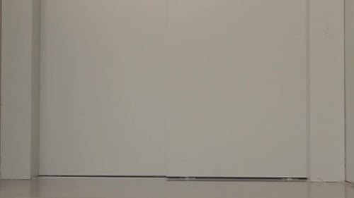 A man entering an elevator to get to the top of his life on a high building. The elevator door open