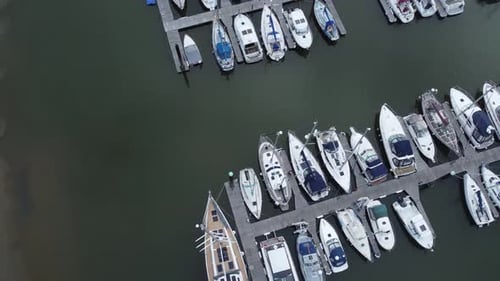 Top down aerial drone view above luxury moored private marina sailing ships and yacht boats orbit ti