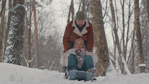 Girl Riding on Snow Sled in Winter Forest