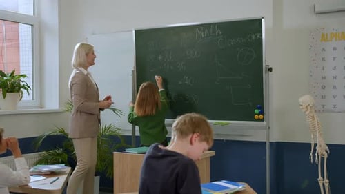 Elementary School Class Children Communicate with the Teacher Answering Question