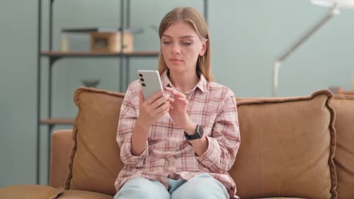 Woman Uses Smartphone on Couch in Bright Home