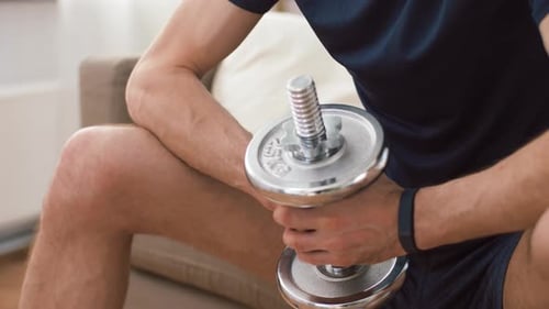 Man Holding Dumbbell While Sitting Indoors