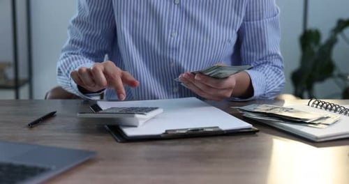 Woman Counts Money and Takes Notes in Office