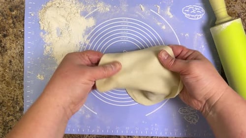 Rolling out round pieces of raw dough with a rolling pin to make patties. Top view.