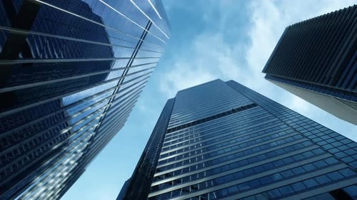 Low angle of modern business architecture with glass and steel walls reflecting sky clouds.