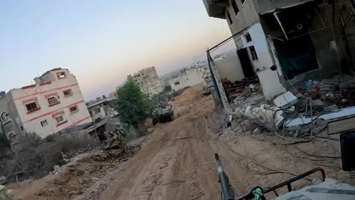 Israeli military armed vehicles, military tankers driving on bombed and destroyed street of Gaza dur