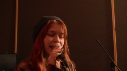 Punk girl Intensely Singing Into Microphone in Dimly Lit Soundproof Studio