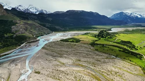 Aerial drone view of winding rivers and green plains stretching between mountains in Patagonia under