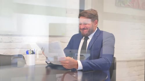 Frustrated Business Man Looking at Paperwork in Office