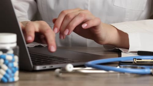 Woman Typing on Laptop in Clinic with Stethoscope