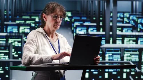 Woman Works on Laptop in Server Room