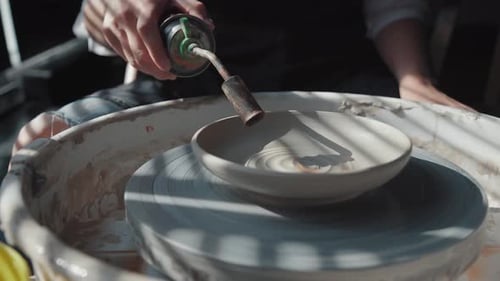 Potter Smoothing Ceramic Bowl with Torch on Wheel