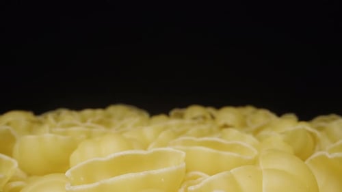 Dry pasta rotates, Scattered evenly on the Table, on a Black background, Close-up. Dolly slider extr