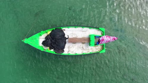 Small Fishing Boat anchored in a shallow lagoon, with packed Fish net onboard