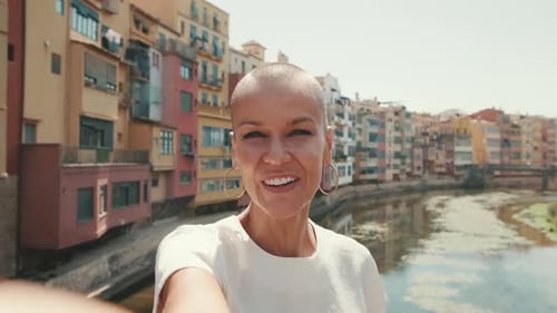 Woman Smiling and Waving on a City Bridge