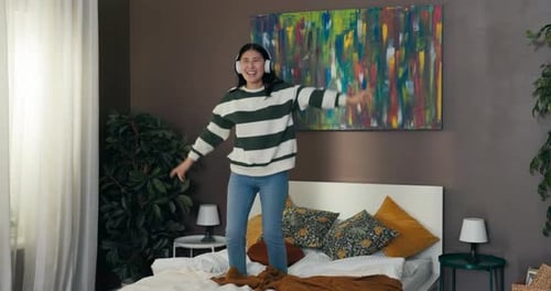 A Young Student Dances in Her Dorm Room While Listening to Music on Wireless Headphones The Girl