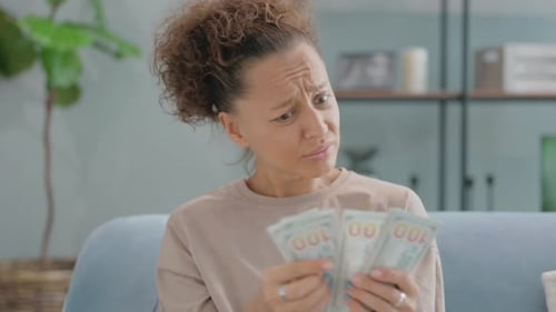 Portrait of Shocked Hispanic Woman Counting Money at Home