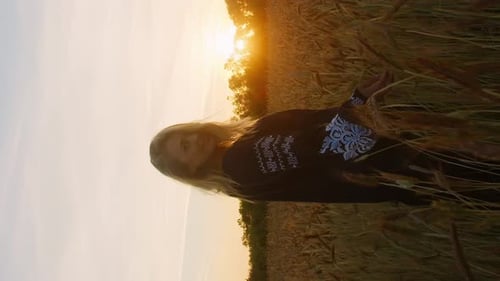 Vertical farmer girl walks through wheat field at sunset touches the wheat ears with hands
