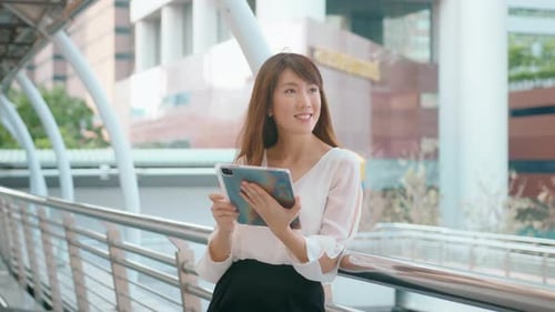 beautiful young asian business woman is using tablet in modern city