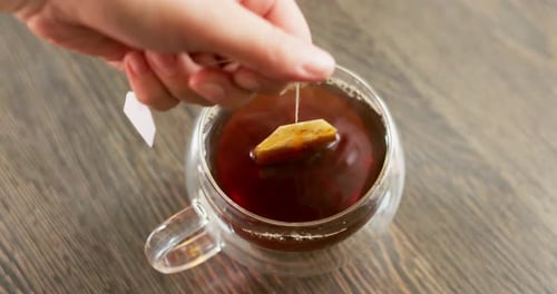 Glasbecher mit schwarzem Teebeutel, Teebeutel ins Klassenzimmer füllen Tasse mit heißem Wasser