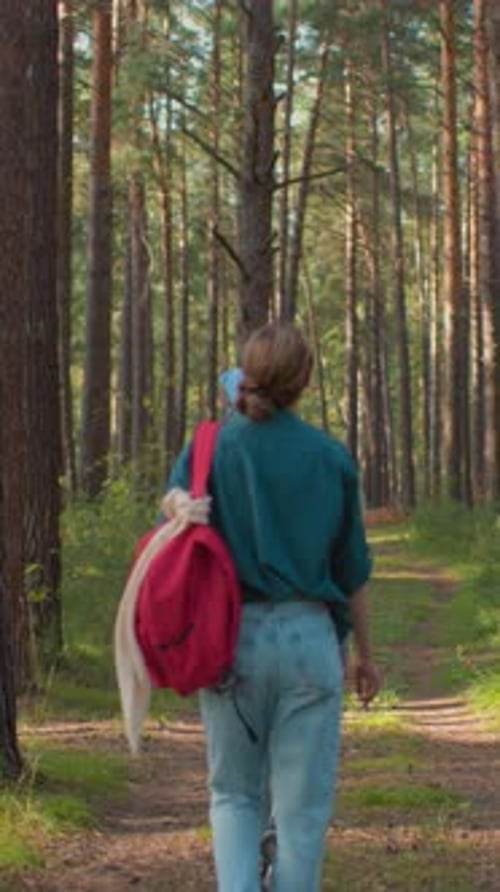 Friends Walking Through Lush Forest Path with Red Backpack and Draped Handkerchief