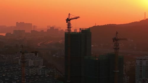Orange Sky Over Construction Site During Sunset Buildings Under Construction with Cranes in the