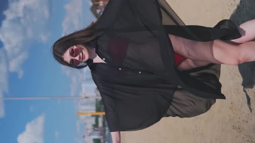 Beautiful, attractive, happy girl posing on a sandy beach on a sunny day in a red swimsuit, sunglass