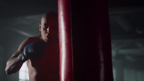 African American Professional Boxer Punching Bag in Dark Gym. Closeup Sportsman Boxing