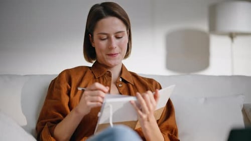 Woman Writing in Notebook on Couch Indoors