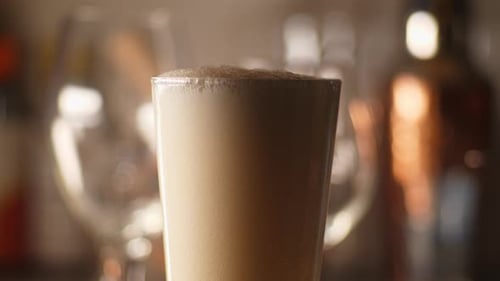 Close up of craft Beer being poured in to an empty pint glass, light background